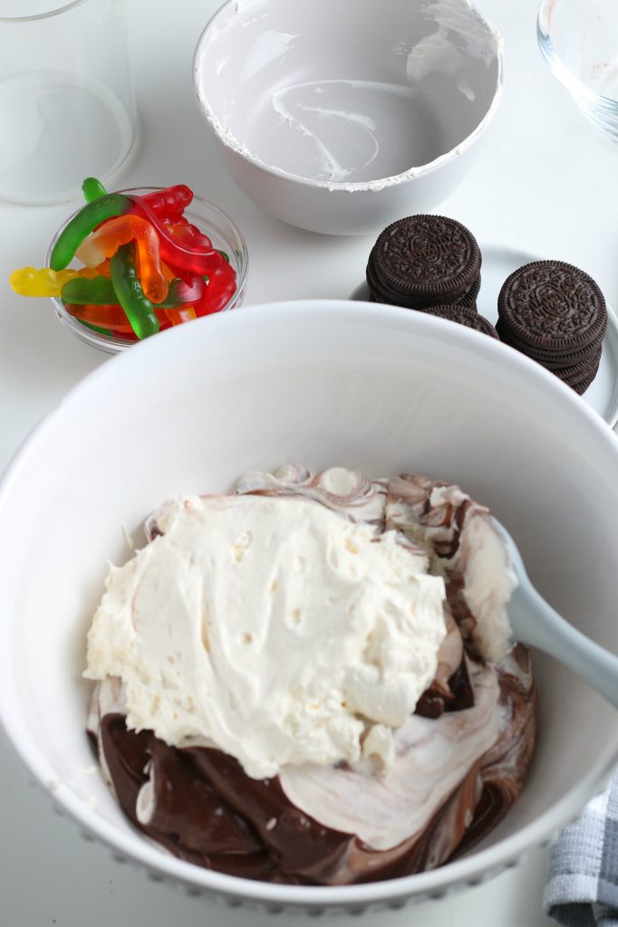 Brown chocolate pudding has been topped with white whipped topping.